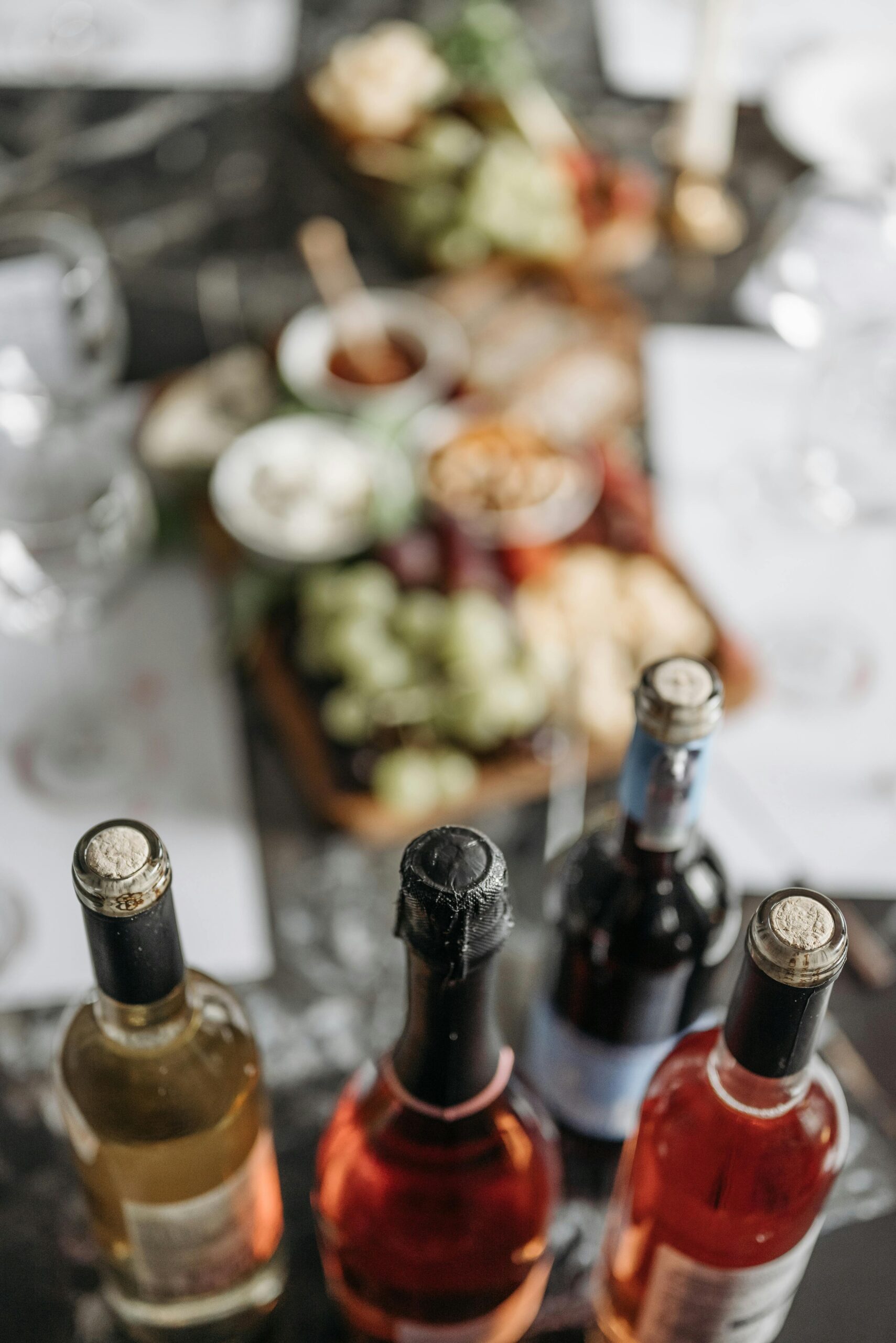 Bottles of wine on a table with a blurred background of gourmet appetizers, creating a sophisticated dining ambiance.